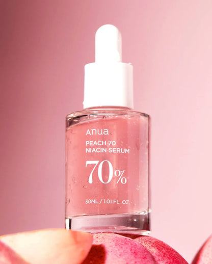 Anua Niacin Hyaluronic Serum in clear bottle with dropper, pink background and peach fruit
