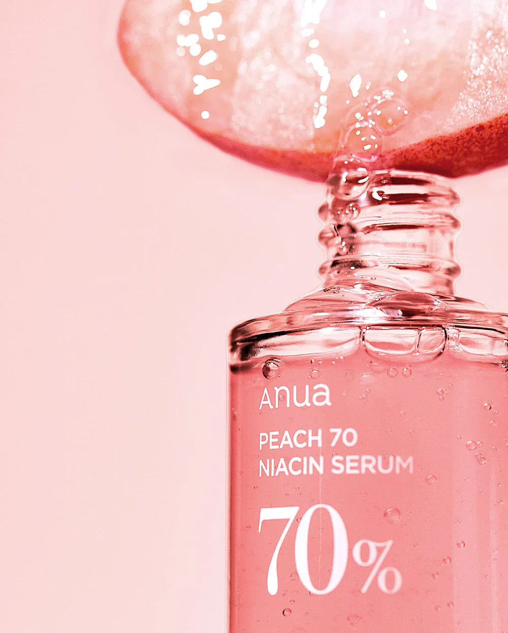 Anua Niacin Hyaluronic Serum Peach 70 Niacin Serum bottle with fresh peach slice on pink background