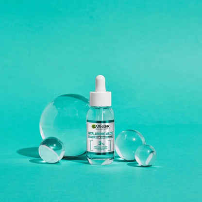 Garnier Skin Naturals Hyaluronic Aloe Serum bottle with clear glass spheres on turquoise background