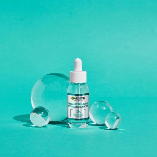 Garnier Skin Naturals Hyaluronic Aloe Serum bottle with clear glass spheres on turquoise background