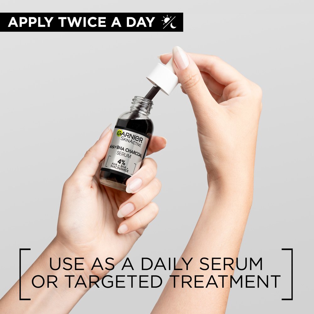 Hands holding Garnier Skin Naturals activated charcoal serum bottle with dropper for daily skincare use
