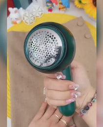 Souqzila portable lint remover trimmer in green held over a beige fabric to remove lint